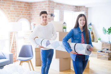 Beautiful young asian couple looking happy, holding rug smiling excited moving to a new home