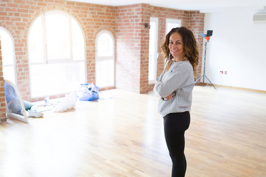 Beautiful middle age woman with curly hair smiling confident at new home, renovating and painting house