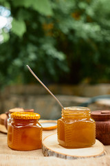 Herbal honey in jar with dipper.  Honey in glass jars and honeycombs wax on stone background
