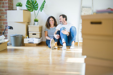 Middle age senior romantic couple in love sitting on the apartment floor with cardboard boxes...