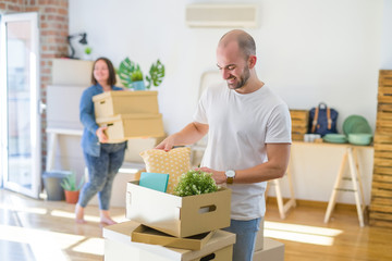 Fototapeta na wymiar Young couple moving to new apartment, handsome man moving cardboard boxes and smiling happy
