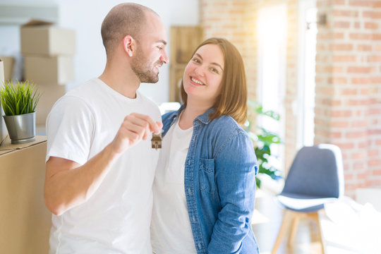 Young couple smiling very happy showing keys of new home, moving and buying new apartmet concept