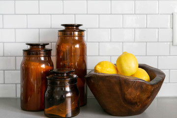 Lemons in Wooden Bowl and Amber Jars on Concrete Kitchen Countertop, White Subway Tile Backsplash