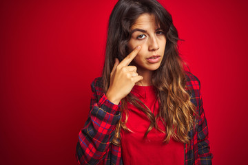 Fototapeta premium Young beautiful woman wearing casual jacket standing over red isolated background Looking fascinated with disbelief, surprise and amazed expression with hands on chin