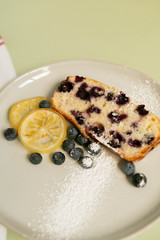 Slice of Iced Lemon Blueberry Loaf Breakfast / Dessert, Pale Green Background, Styled Shot, Top View Flat Lay