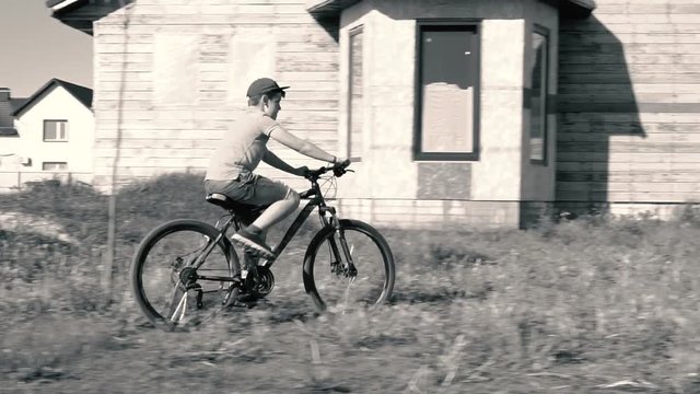 The boys ride bikes.  Countryside.  Warm season.  Bright sun.  Competition for children.  Bicycle movement.  Black and white image.