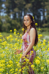 Naklejka na ściany i meble Mixed race young woman stands in a flower field on a farm