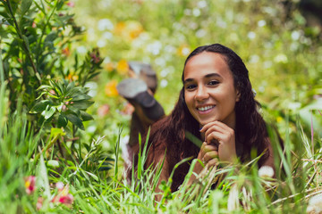 Mixed race young woman reclines in grass on a farm