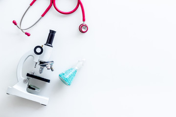 Medical tests on work table of doctor with microscope, stethoscope, test tube, pills on white background top view mockup