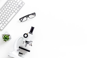 Desk of doctor in laboratory with microscope, keyboard for medical research on white background top view copyspace