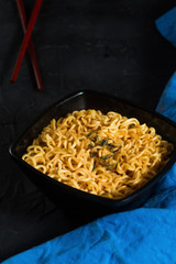 Ramen noodles bowl on a dark textured background with dark wooden chopsticks