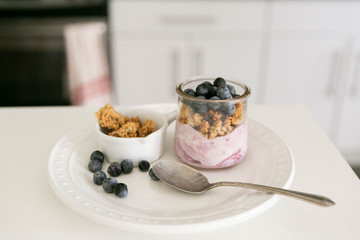 Blueberry Yogurt in Clear Glass with Fresh Blueberries and Honey Granola, Modern Kitchen Background
