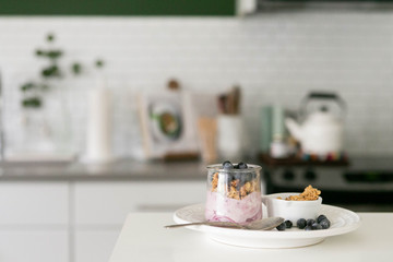 Blueberry Yogurt in Clear Glass with Fresh Blueberries and Honey Granola, Modern Kitchen Background