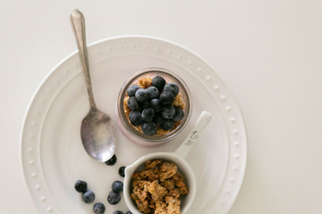 Yogurt with Fresh Blueberries and Honey Granola, Top View, White Background, Copy space