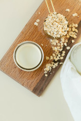 Fresh Oat Milk in a Clear Glass with Bottle, Loose Oats, Off-White Background, Homemade, Top View