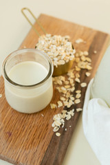Fresh Oat Milk in a Clear Glass with Bottle, Loose Oats, Off-White Background, Homemade, Top View