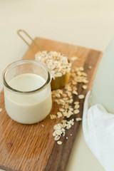Fototapeta na wymiar Fresh Oat Milk in a Clear Glass with Bottle, Loose Oats, Off-White Background, Homemade, Top View