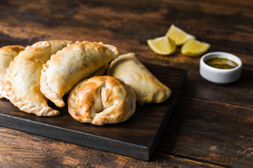 Traditional baked Argentine empanadas savoury pastries with meat beef stuffing against wooden background