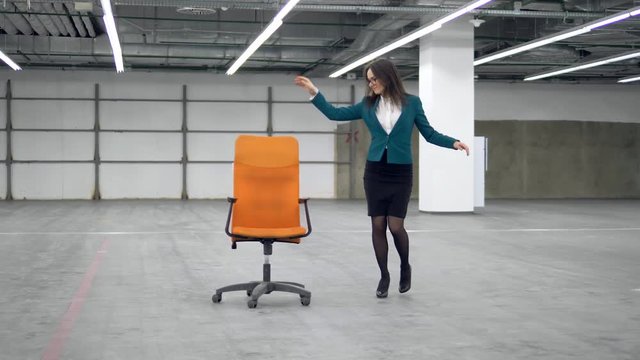 Female manager is dancing with a rolling chair along the hall