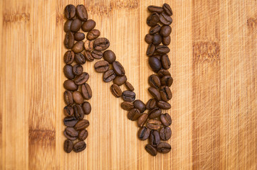 Alphabet letter N made from roasted coffee beans, 3D rendering on wooden table background