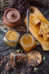 A table with a wicker table top, honey in honeycombs on a wooden board, honey in an open glass jar,...