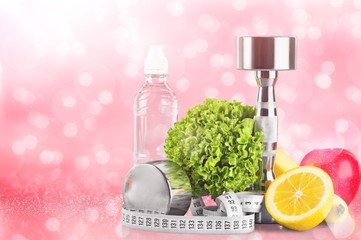 Dumbbell with bottled water , measuring tape and fruits isolated