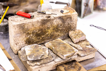 View on a wooden work bench equipped with tools for the making of jewellery and metal processing with different inflammable surfaces