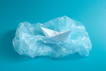 Ban plastic pollution. Paper ship on the globe, wrapped in a plastic bag. Creative concept