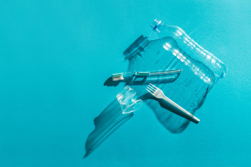 Stop plastic contamination at sea, discard disposable plastic products. Plastic cutlery, cup, toothbrush, bottle on a turquoise background