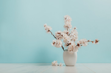 Spring bouquet in a white vase, white frame on the table. Mockup