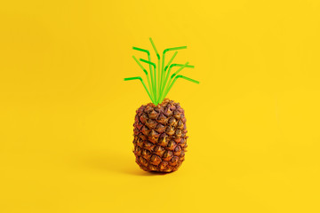Pineapple on a yellow background with a straw. Creative concept summer drinks and juice