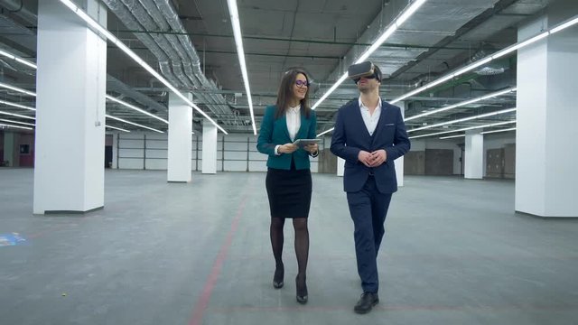 Female estate specialist is showing property to a man in VR-glasses. Commercial real estate.