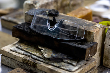 Close up of a wooden work bench for precious metal cultivation with several inflammable surface materials and protective glasses