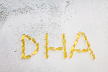 capsules laid out in the form of letters DHA. Close up gold capsules of omega-3 .