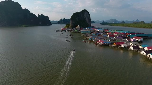 An establishing shot of boats sailing back to a settlement surrounded by water in Thailand