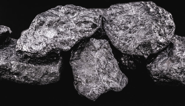 Manganese in the raw state. Manganese stone isolated on black background. Mineral extraction of heavy metal.