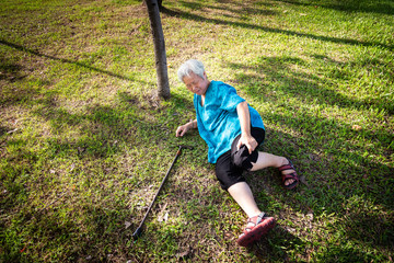 Asian elderly people with walker on floor after falling down in outdoor park,sick senior woman fell to the floor because of dizziness,faint, accident,suffering from illness, leg,knee pain or bone pain