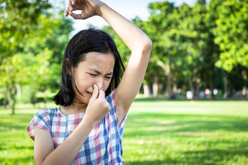 Closeup asian cute girl feel bad foul odor situation,smelling,sniffing her wet armpit in outdoor,...