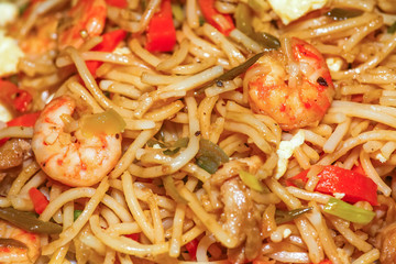 Tasty chicken noodles meal with prawn and egg in close up macro view. Mixed chowmein noodles with vegetables is a popular Chinese cuisine in India