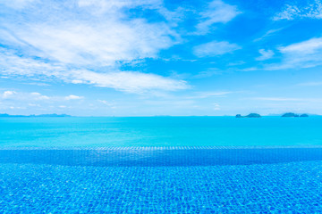 Beautiful luxury outdoor infinity swimming pool with tropical sea ocean and white cloud blue sky...
