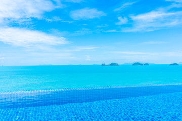 Beautiful luxury outdoor infinity swimming pool with tropical sea ocean and white cloud blue sky background