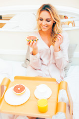 young beauty blond woman having breakfast in bed early sunny morning, princess house interior room, healthy lifestyle concept