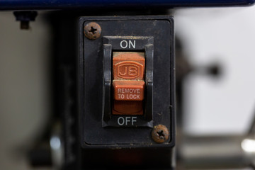 Close up of a vintage red on and off button on a small old industrial machine