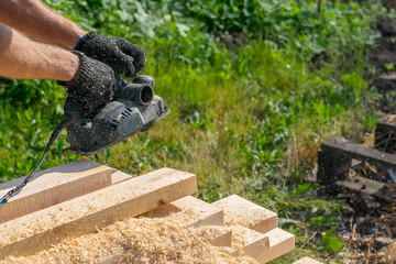 man planing boards with electric tools, chips flying in all directions. Construction, wood processing