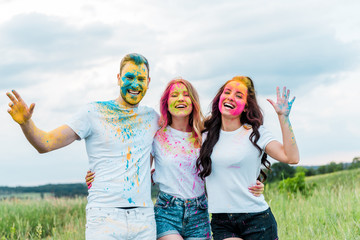 happy group of friends with holi paints on faces smiling outdoors © LIGHTFIELD STUDIOS