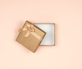 open golden gift box with a bow on a beige background