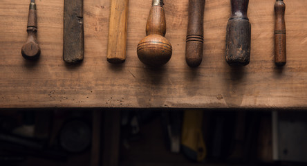 Handles for the job. Old and well used tool handles or grips aligned on an old work bench. each...