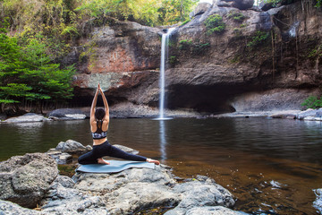 Young girl asian women is playing  yoga in front of the waterfall.