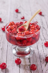 Glass bowl with fresh homemade cherry jam on wooden table.