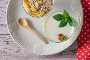 Yogurt with strawberries and mint and oatmeal on a wooden table. Flat lay.